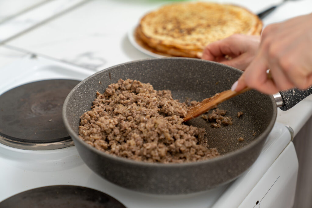 Ground beef cooking in a skillet with a wooden spatula for an easy recipe base.