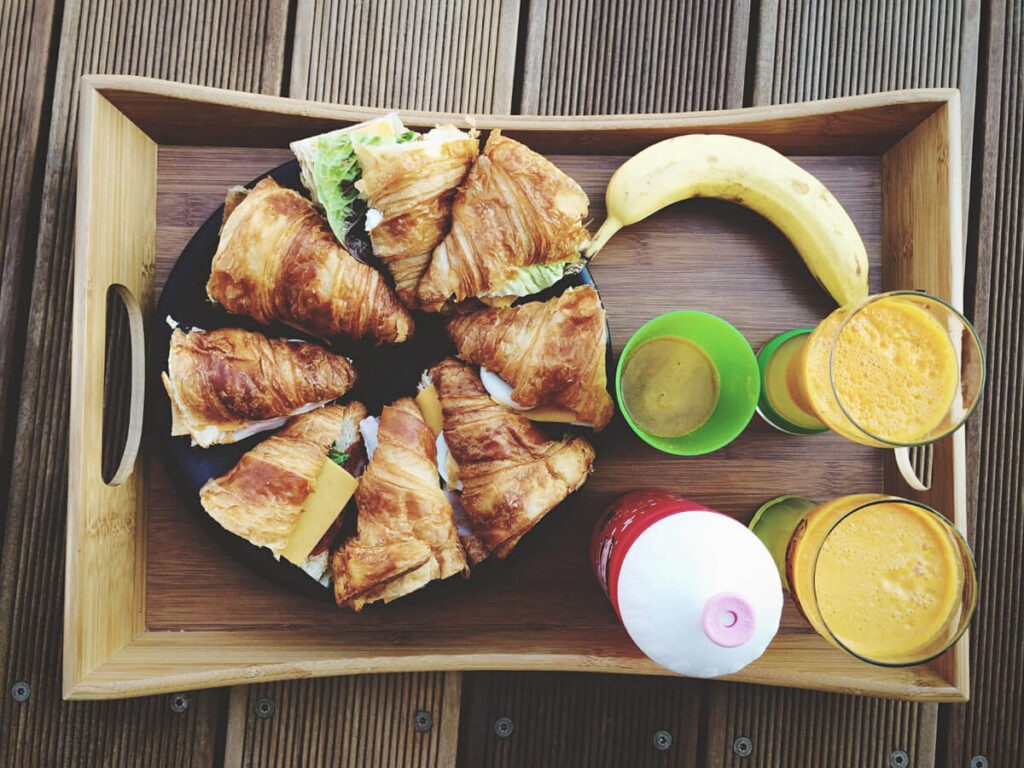 Golden breakfast croissant sandwich with eggs, cheese, and bacon on a rustic wooden plate