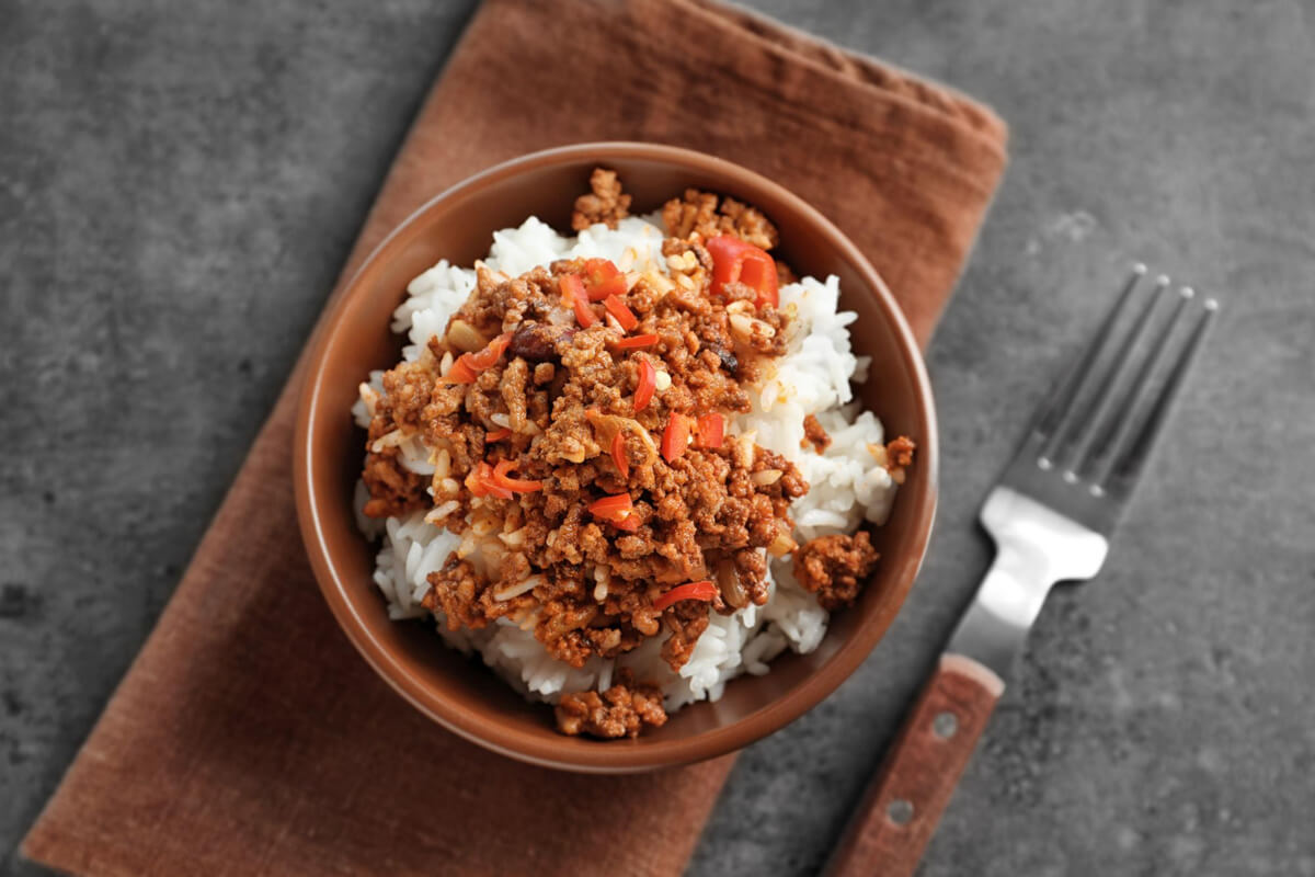 A delicious ground beef and rice bowl garnished with fresh parsley and colorful vegetables.