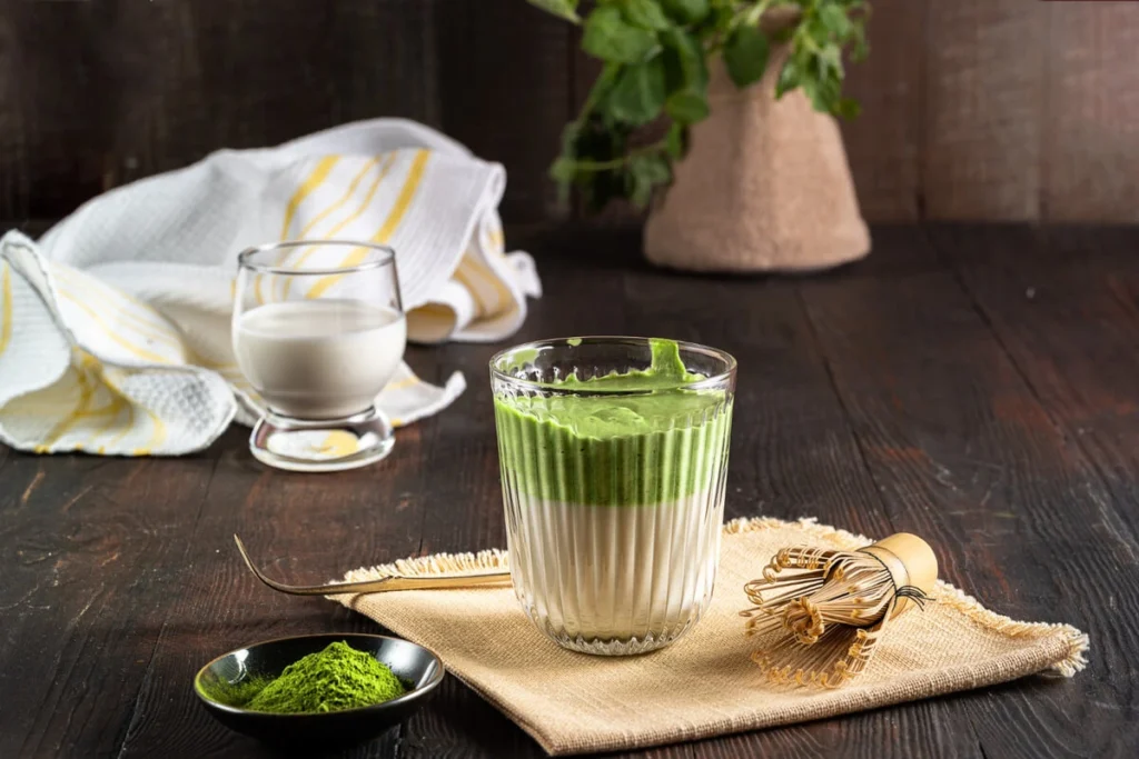 How do I make my matcha latte taste better? A vibrant green matcha latte with froth and bamboo whisk.