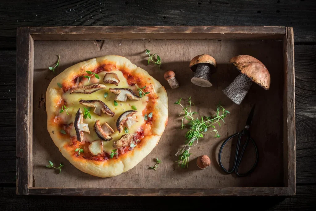 Gourmet naan pizza with basil and cherry tomatoes on a wooden board.