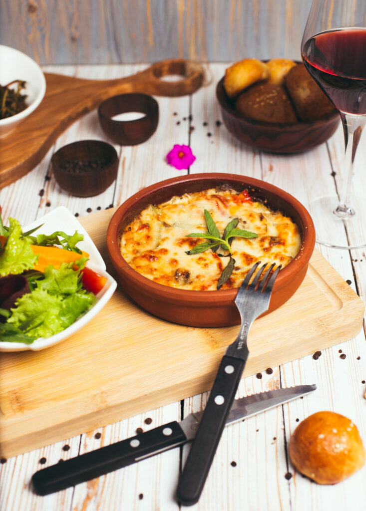 A freshly baked spaghetti casserole with melted cheese in a glass dish on a rustic table.