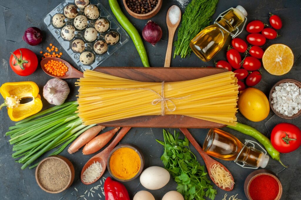 Ingredients for spaghetti casserole, including spaghetti, marinara sauce, ground beef, mozzarella, Parmesan, garlic, and onion.