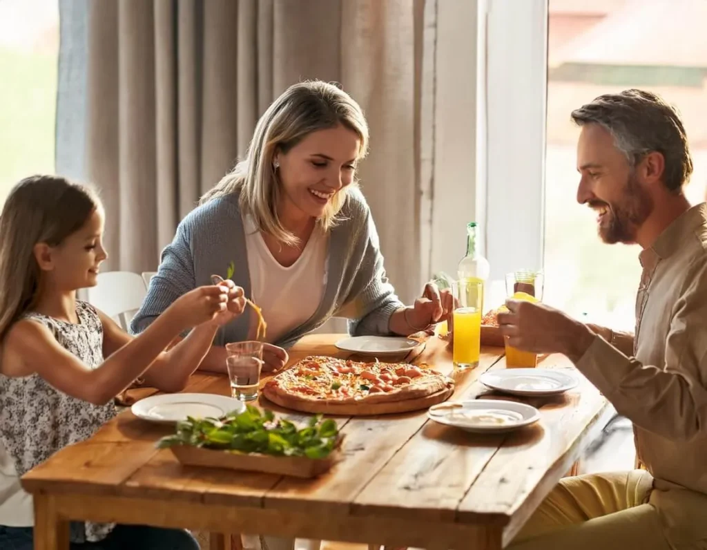 A happy family sharing homemade low-carb pizza around the dining table.