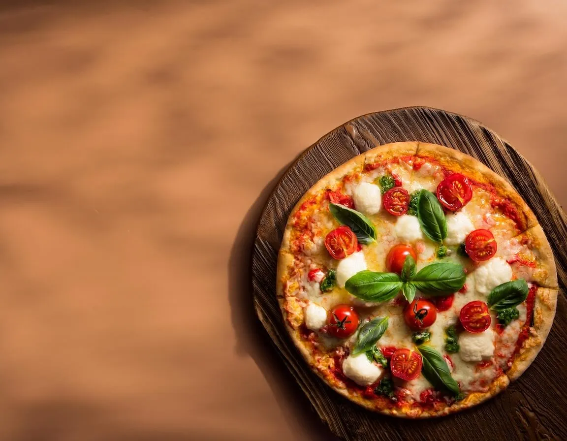 Freshly baked cauliflower crust pizza with cherry tomatoes and basil.