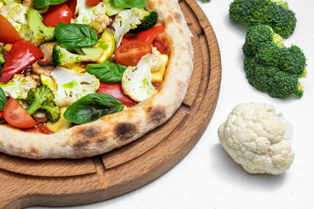 Cauliflower crust pizza topped with fresh vegetables and melted cheese.