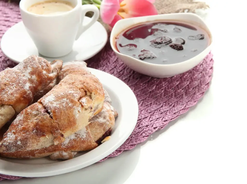 A freshly baked croissant French toast bake garnished with powdered sugar and berries.